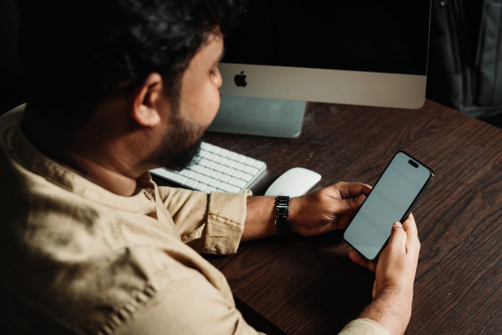 Profesional revisando el celular en su escritorio de oficina, reflejo de la hiperconectividad laboral fuera de horario