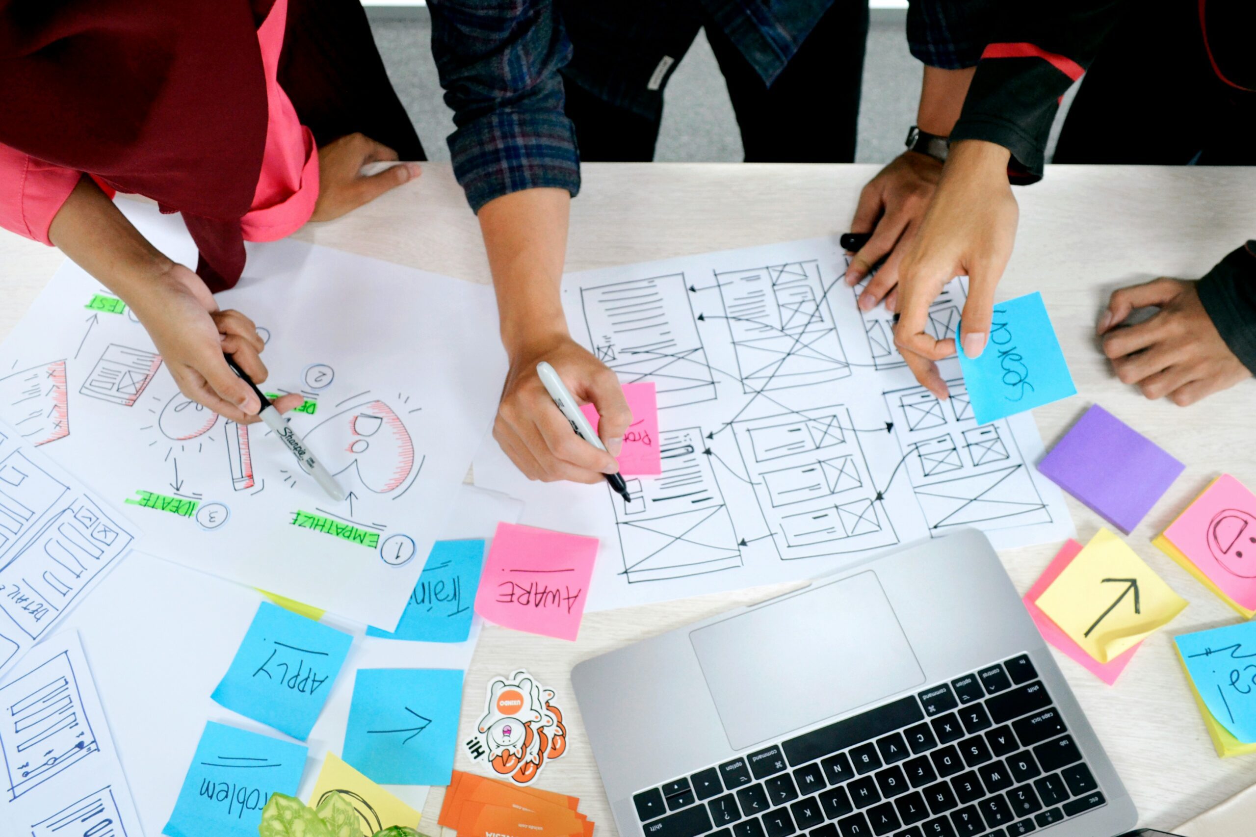 Equipo diseñando un programa con lógica de diseño de experiencia de aprendizaje sobre un tablero con notas y wireframes