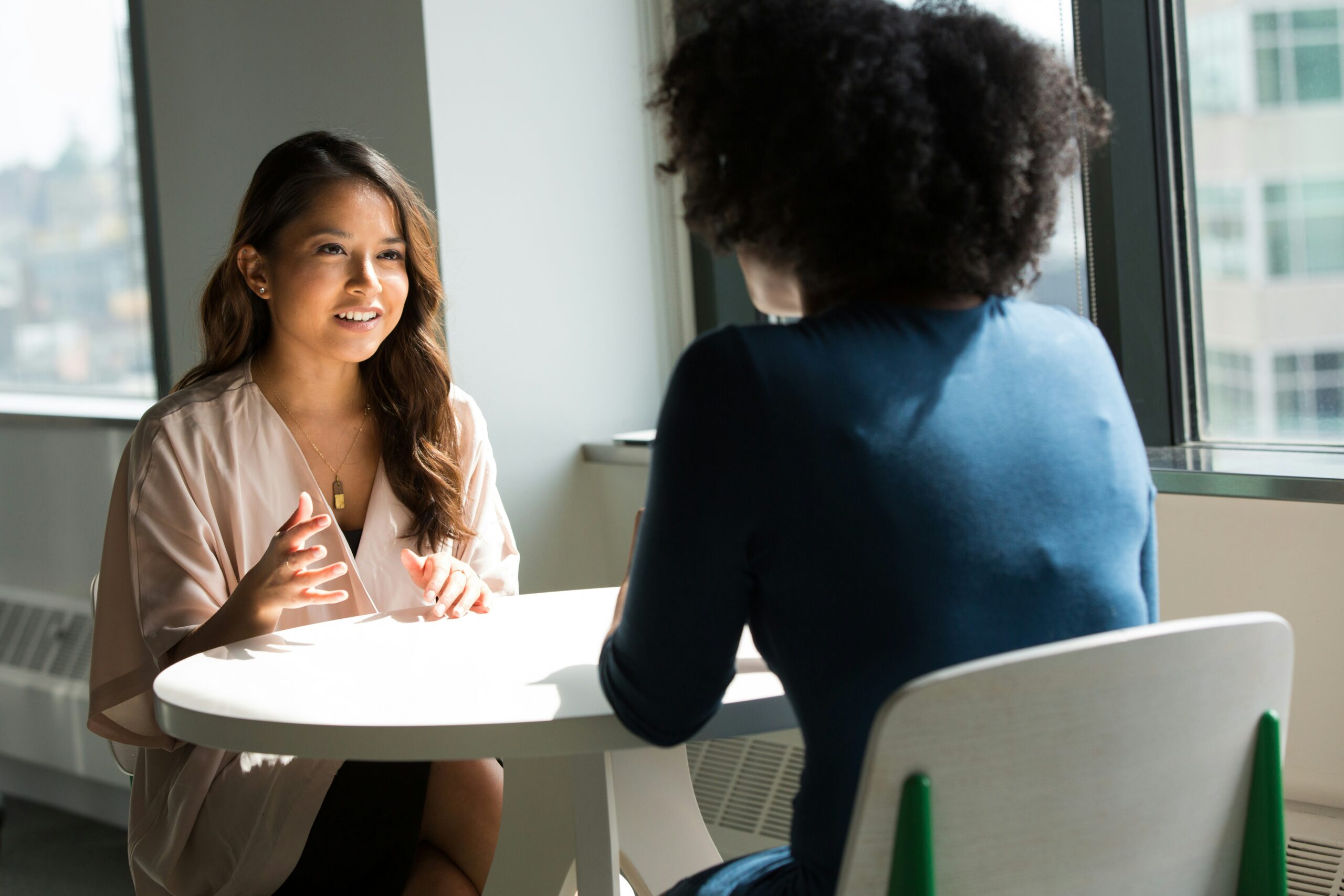 Dos profesionales conversando en un programa de mentoría corporativa dentro de una oficina